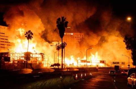 Huge flames extending from wood construction site near Los Angeles freeway.