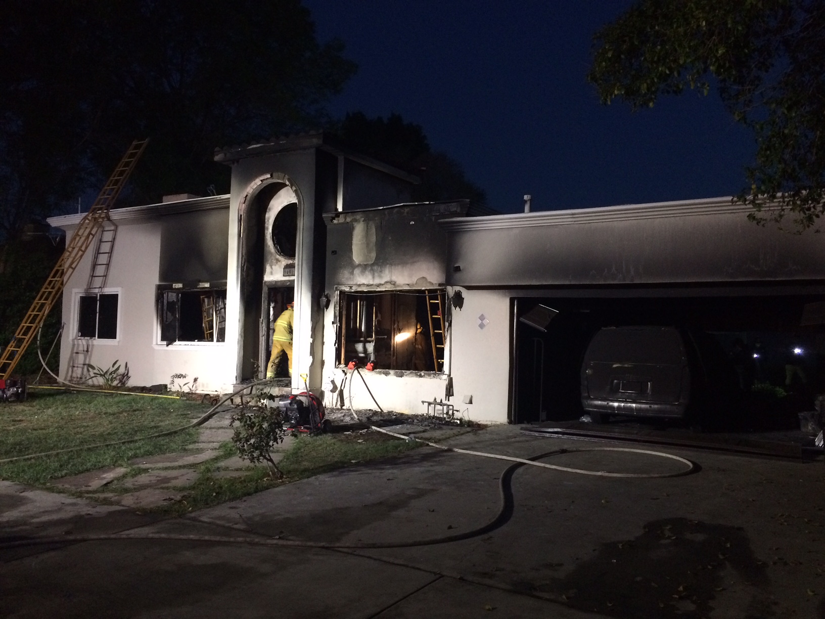 Front view of home after fire, damage visible.