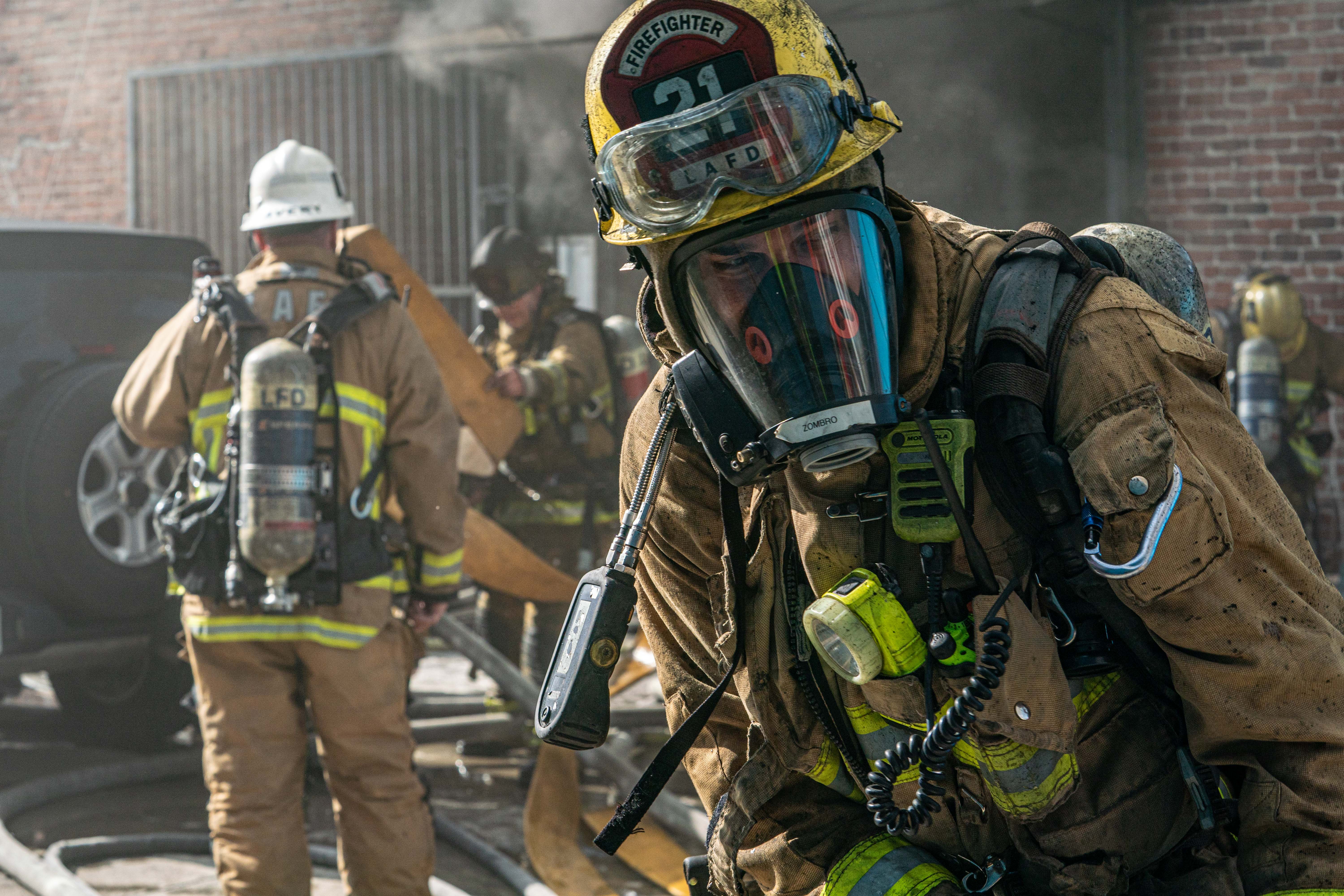 Firefighter in full gear with other firefighters in background at the fire