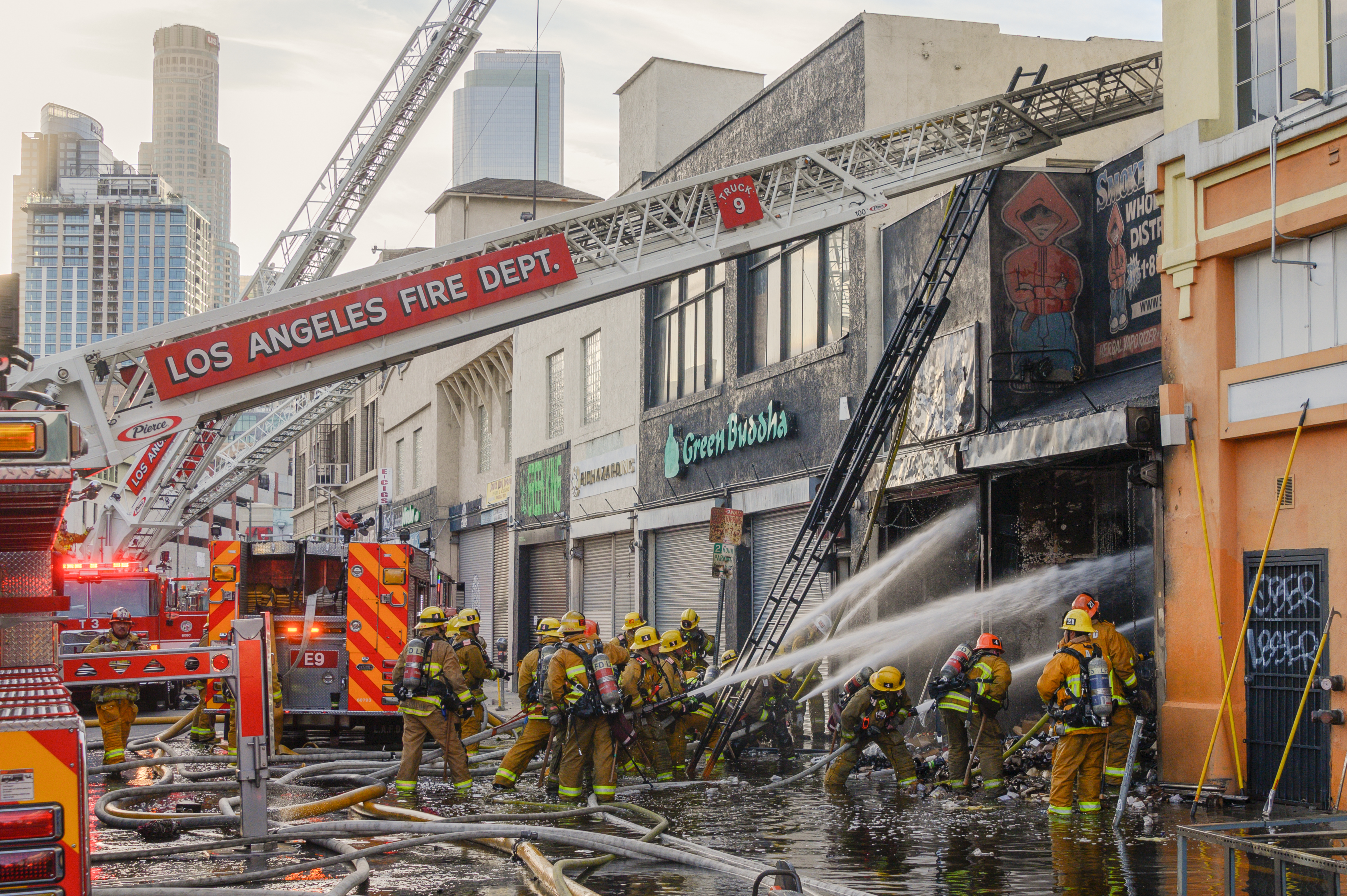 firefighters seen outside a commercial structure fire with handlines