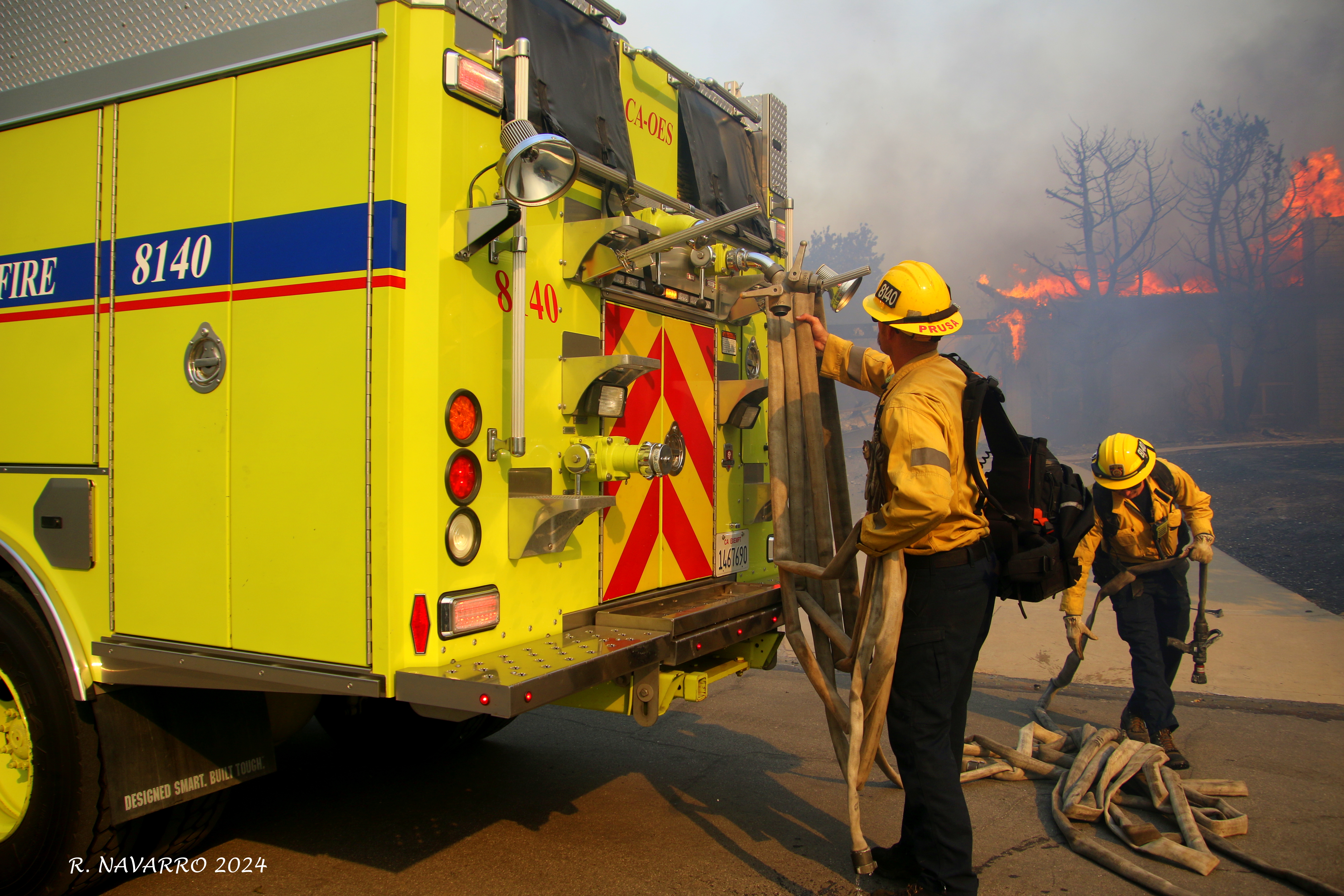 Two firefighters at back of fire engine