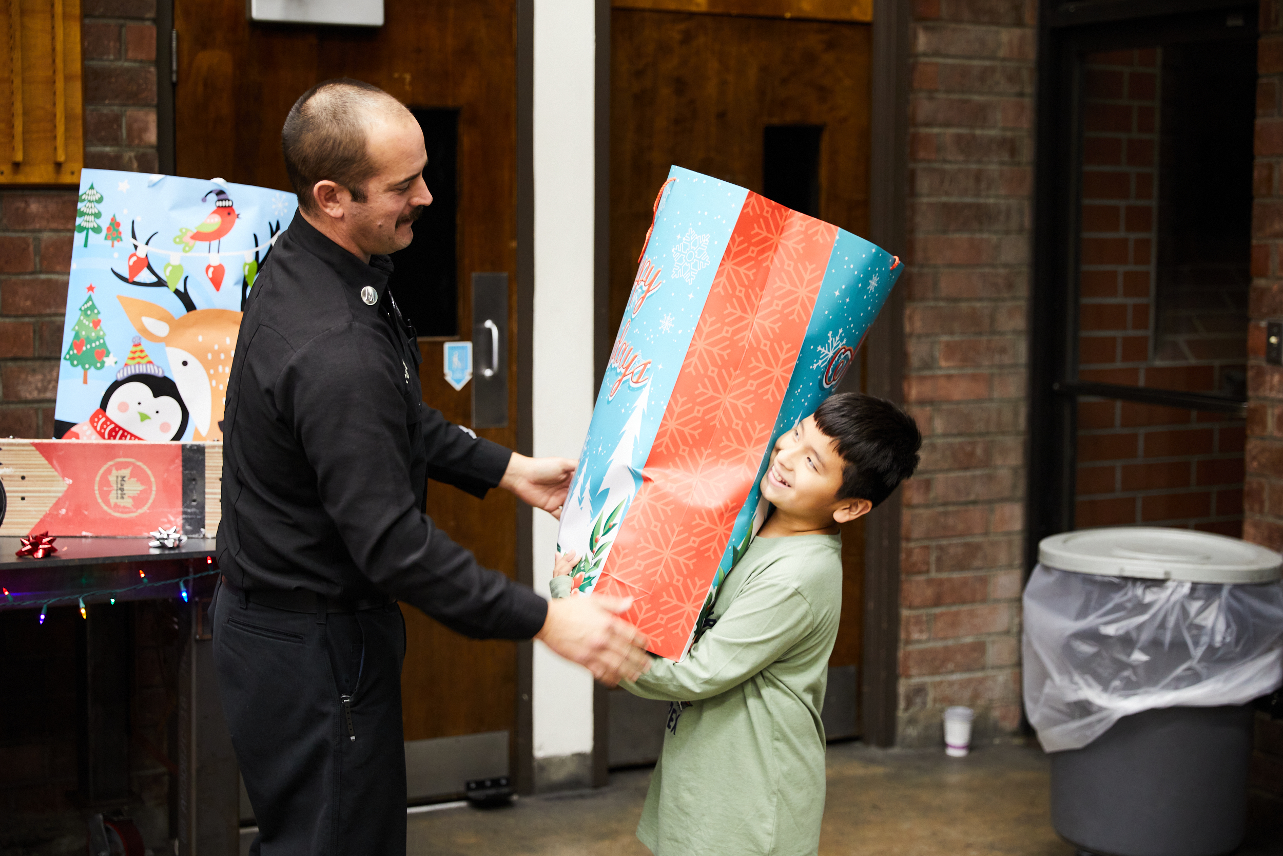 Fire captain presenting gift back to a smiling young boy