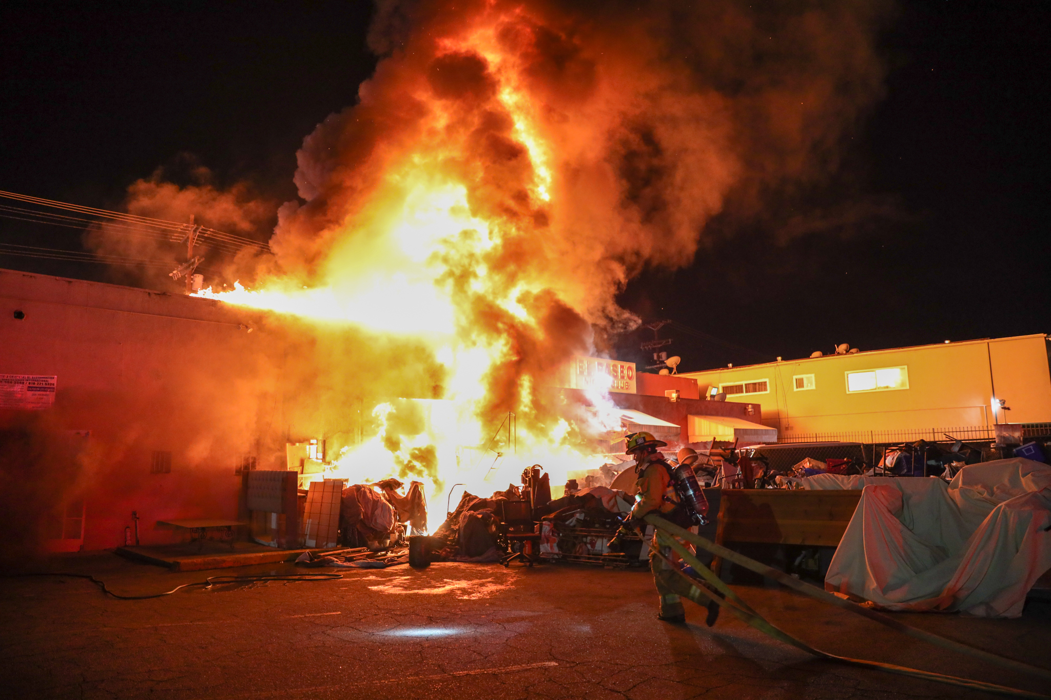 Fire blowing out building as firefighter approaches