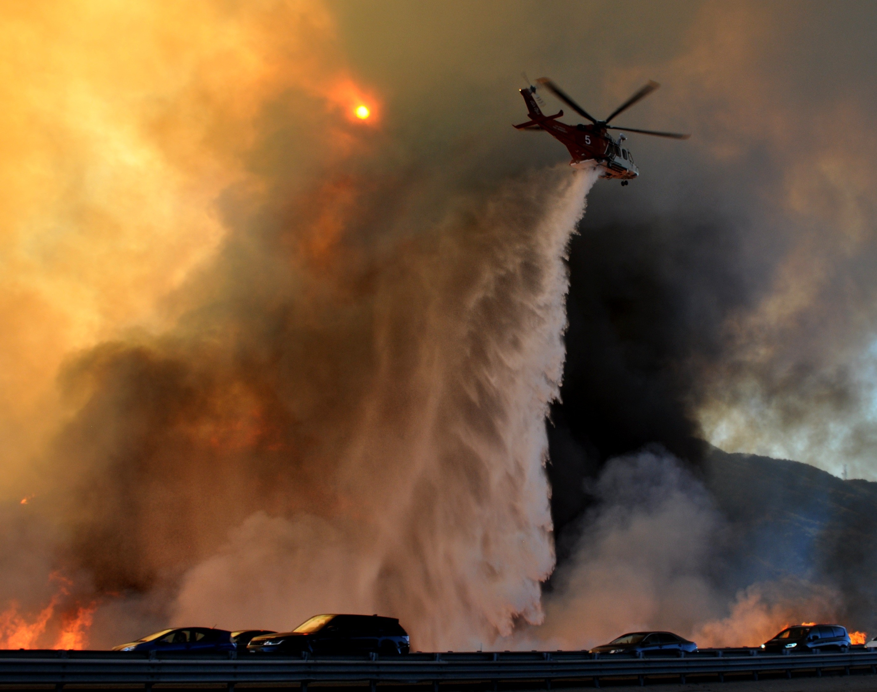 Helicopter dropping water over a brush fire