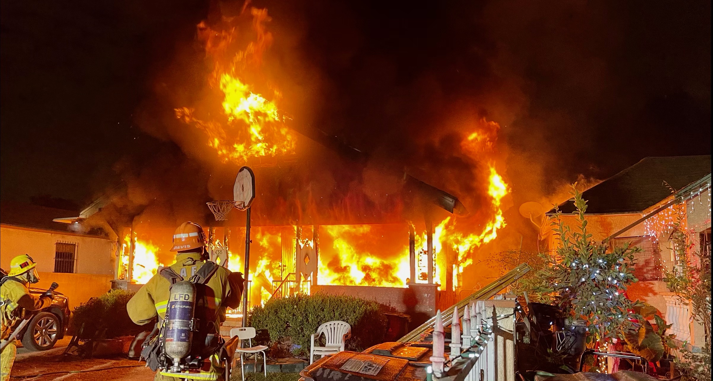 Single family home with heavy fire showing from the front and firefighters visible