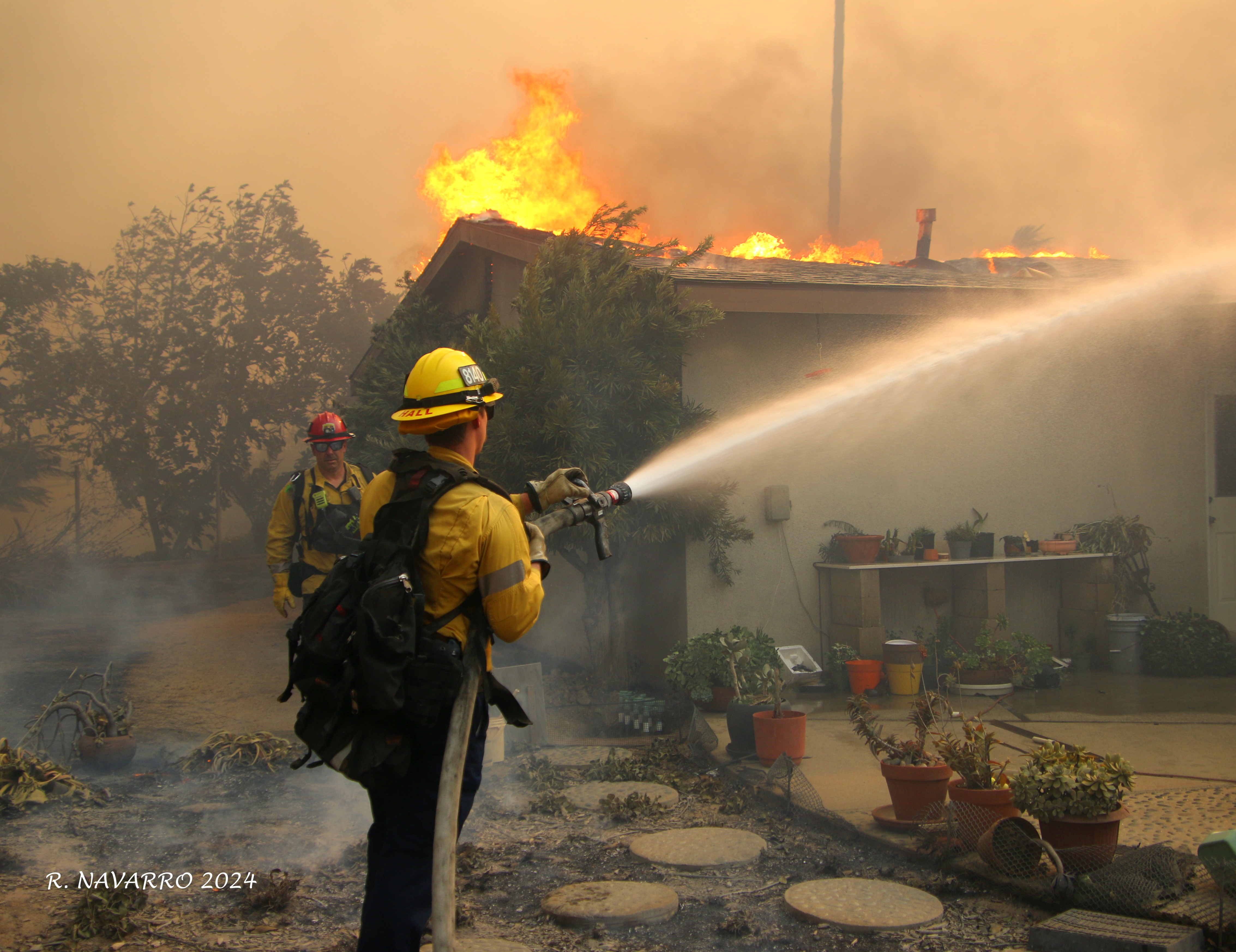 Firefighter with hoseline fighting house fire