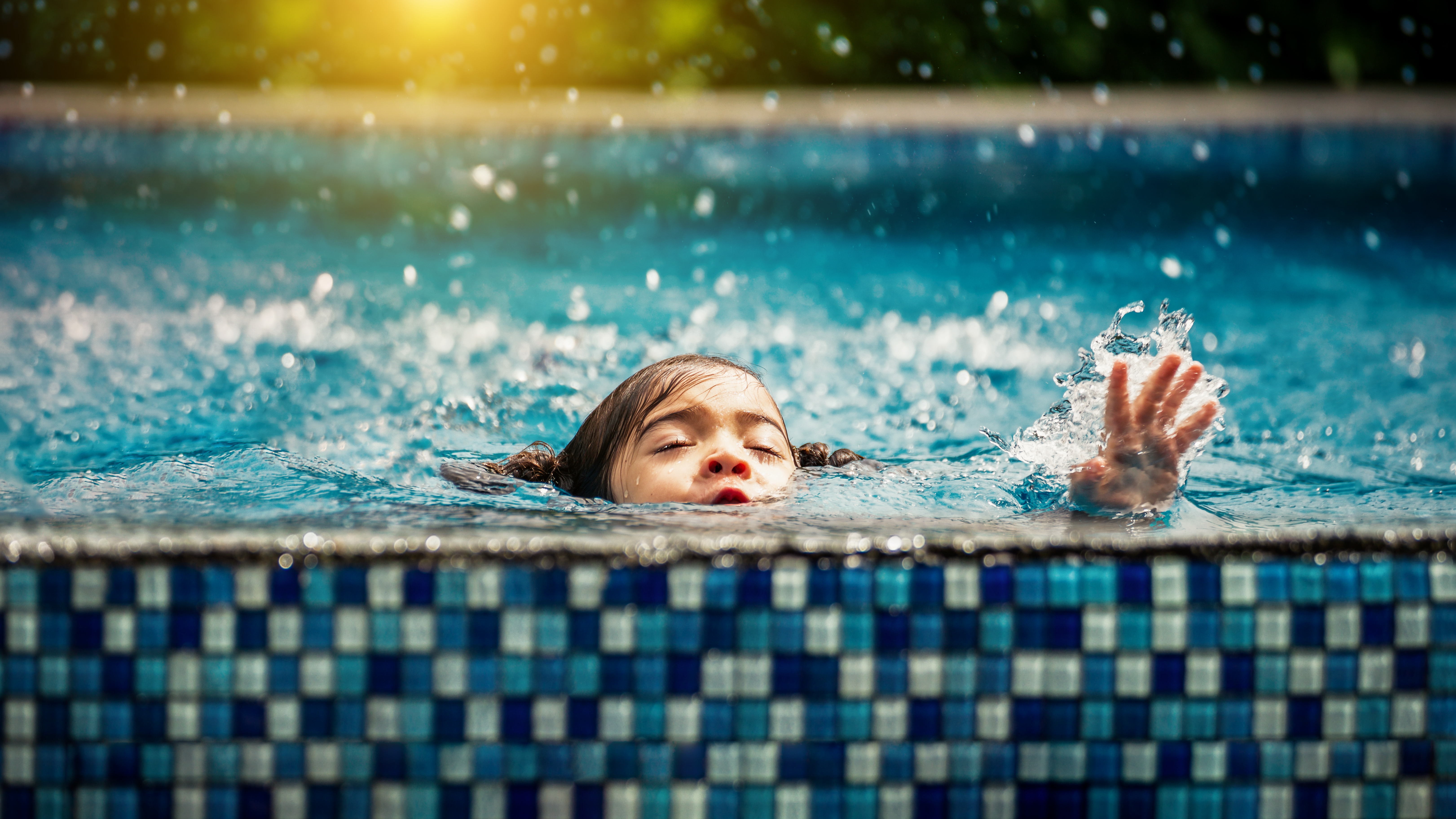 small girl appears to be drowning at the side of a pool